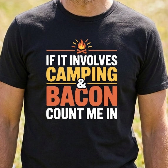 A man wearing a black graphic t-shirt with the text 'IF IT INVOLVES CAMPING & BACON COUNT ME IN' in white, yellow, and orange lettering, standing in a grassy outdoor field.