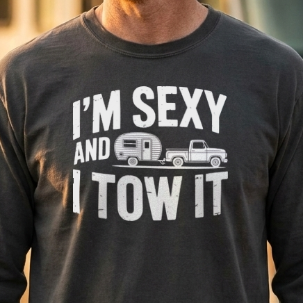 Close-up of a charcoal gray long sleeve shirt with a white I'm Sexy and I Tow It design of a camper behind a pickup