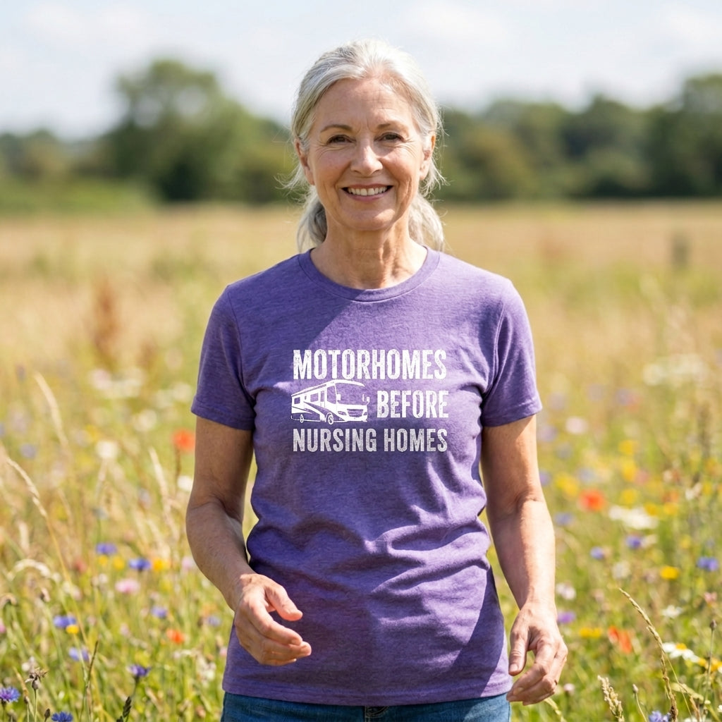 Smiling woman with gray hair in a heather purple Motorhomes Before Nursing Homes t-shirt in a wildflower field.