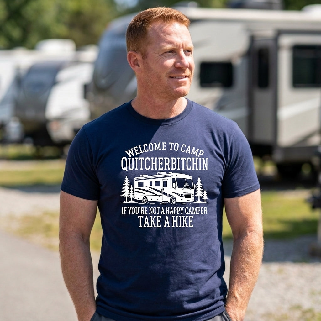 Man in a navy blue Welcome to Camp Quitcherbitchin t-shirt with white text, standing outdoors with RVs behind him.
