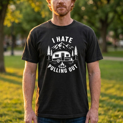 A man wearing a black graphic t-shirt with a white camping-themed print that reads 'I HATE PULLING OUT!' in an outdoor park setting.