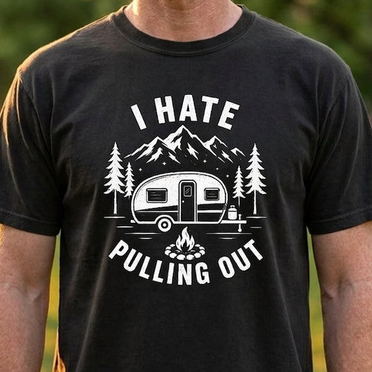 A man wearing a black graphic t-shirt with a white camping-themed print that reads 'I HATE PULLING OUT!' in an outdoor park setting.