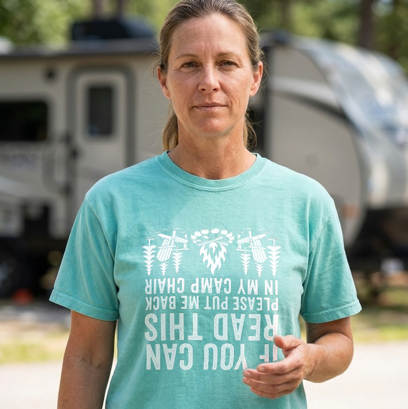 Woman in a teal If You Can Read This camp chair t-shirt with white text, standing outdoors in front of a blurred RV and trees.