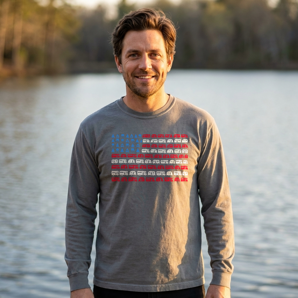 Man by a lake in a gray long sleeve shirt with an American flag design made of RVs and camping icons