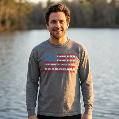 Man by a lake in a gray long sleeve shirt with an American flag design made of RVs and camping icons